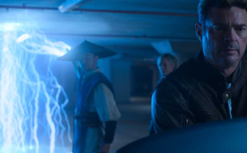 Johnny Cage (Karl Urban) stands in the extreme foreground of a shot as Raiden (Tadanobu Asano) lights up the area with lightning in Mortal Kombat II
